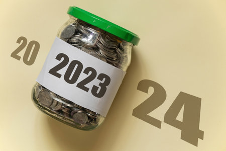 2023 is written on a bank of pennies which lies on a brown background with the text 2024, business in the new year and income, profitの写真素材