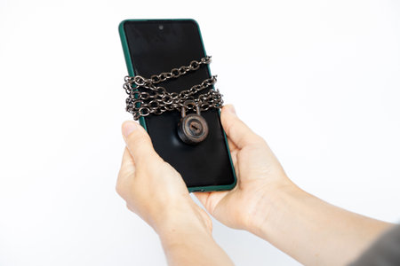 Mobile phone tied with on a chain padlock in the hands of a girl , protection in security of the phoneの写真素材