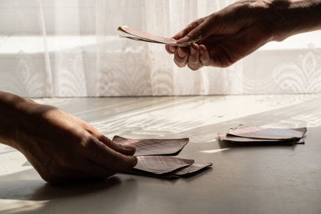 Playing cards at the table near the window at home, gambling board gamesの写真素材