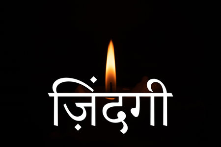 The word life is written in Hindi language on the background of a burning candle in the dark, faith and religionの写真素材