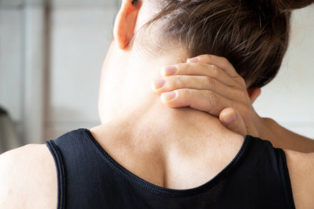 A young girl holds her hand on her neck from back pain at home, back pain