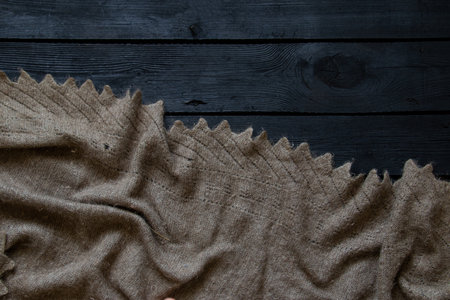 An old grandmother's wool scarf lies on a black wooden floor as a background, fashion and decor, a warm floorの写真素材