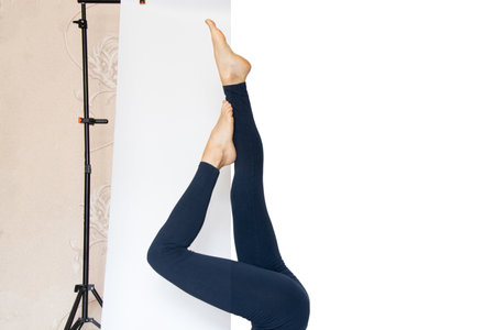 The girl goes in for sports, does fitness, lifts her legs up, trains and does yoga, a photo with a background change on an example before and after changing the background to whiteの写真素材