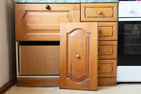 Old wooden kitchen cabinet in the kitchen with a broken door in a Ukrainian apartment, kitchen furniture, furniture repairの写真素材