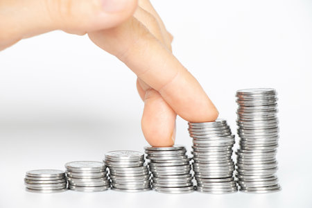 Women's fingers step on stacks of coins on a white background, business and success, financeの写真素材