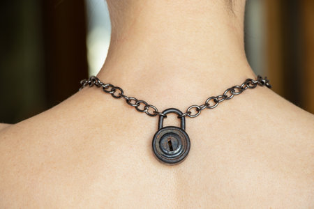 Padlock on a chain on the back of a girl, a man on a chainの写真素材