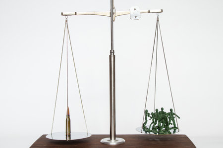Plastic green soldiers and a bullet are on the scales, the weapon balances with soldiers, war and armyの写真素材