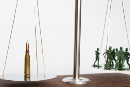 Plastic green soldiers and a bullet are on the scales, the weapon balances with soldiers, war and armyの写真素材
