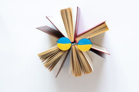 The flag of Ukraine is drawn on glasses that lie on open books on a white background, education in Ukraineの写真素材