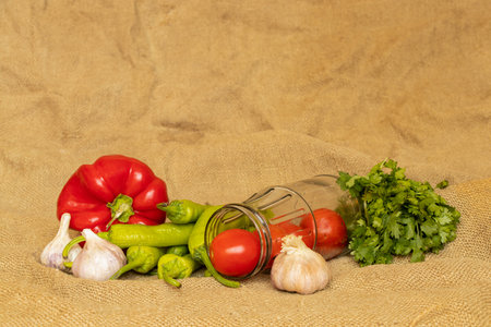 Peppers and garlic and tomatoes and hot peppers and jars lie on a sackcloth, cooking ingredients for adjika, vegetablesの写真素材
