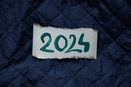 2024 is written in green ink on a paper card lying on a blue quilted background, Happy New Year 2024, bannerの写真素材