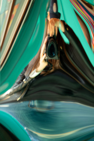 Girl photographer with a camera, distorted in a distorted mirror, a distorted mirror as a background