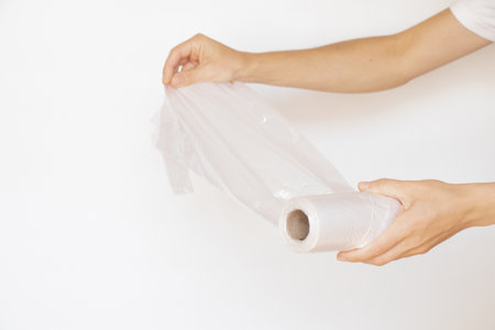 Female hands hold a roll of disposable plastic bags on a white background, disposable bags, plastic...
