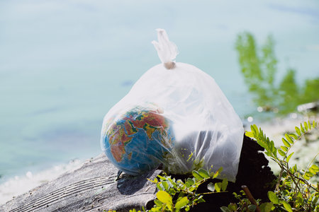 A globe in a plastic bag lies on a discarded tire near water in Ukraine, environmental pollution,...