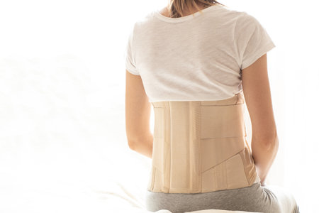 Woman with a corset on her back to support her back from pain in the back and spine, Medical concept, spinal support, wearing a brace at homeの写真素材