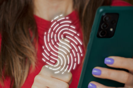 The girl presses her fingers on the virtual fingerprint of the phone, password and data security, technologyの写真素材