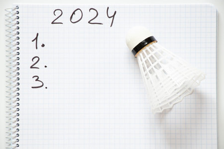 2024 and the numbers 123 are written in a notebook and a shuttlecock lies next to it on a white background, planning for the new year 2024の写真素材
