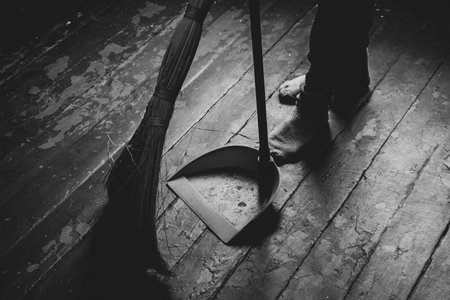 Womens feet on the floor and a broom and dustpan nearby, a girl sweeping the floor of the house, black and white photoの写真素材