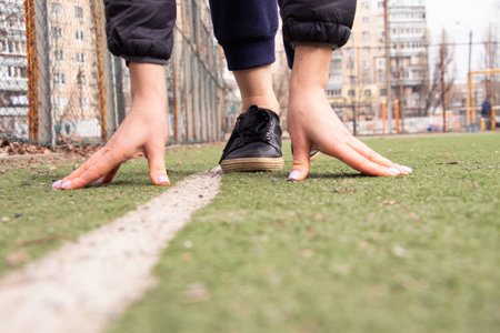 Hands and feet of a runner in sneakers on the starting line at the stadium in the courtyard in the city of Dniproの写真素材