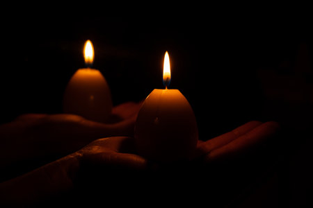 A yellow candle in the shape of an egg in a girl s hand in the dark, Easterの写真素材