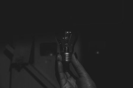 An incandescent lamp in the hands of a girl in the corridor near the meter, black and white photo, without lightの写真素材