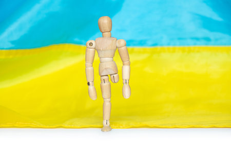 A wooden man without a leg against the background of the Ukrainian flagの写真素材