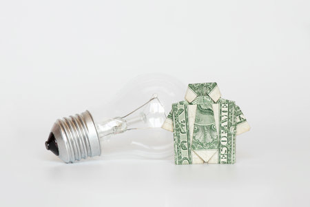 Dollar shirt and incandescent lamp on a white background, light price and tariff, moneyの写真素材