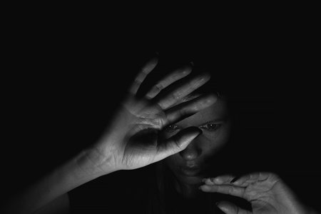 Girl in the dark covers her face with her hands from the light at home, black and white photo, girl...