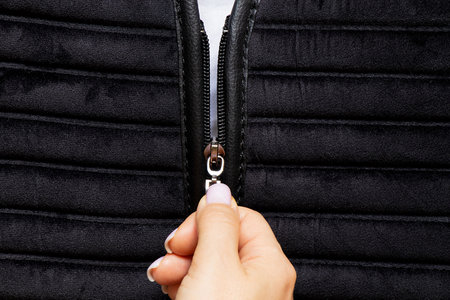 Female hand unzipping black clothes as background,zipperの写真素材