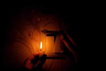 Woman's hand with a candle in the dark of the house near the switch and sad emotions drawn on paper,...