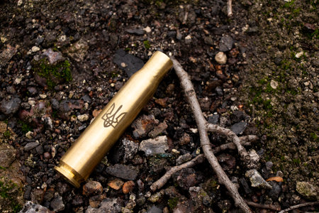 An empty cartridge case with the coat of arms of Ukraine lies on the ground in Ukraine during the...