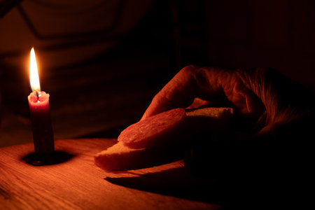 Grandma holds a piece of bread with sausage at home without electricity in Ukraine due to rocket...
