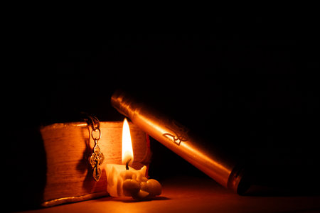 Coat of arms of Ukraine on a cartridge case and a silver cross and a bible near a candle in the dark of a houseの写真素材