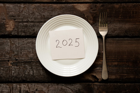 2025 written on paper lying on a plate on a wooden old board close-upの写真素材