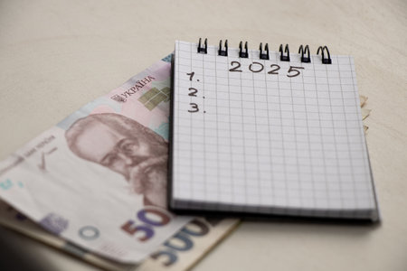 2025 and 123 written in a notebook and Ukrainian 50 hryvnia which is lying on the table, plans for...