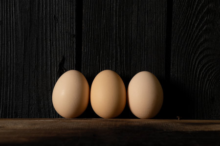 Three chicken eggs on a wooden background.の写真素材