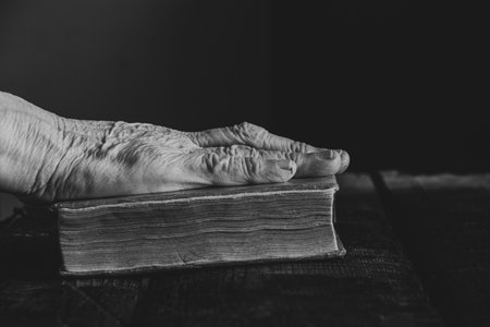Elderly woman reading a book at the table at home, black and white photoの写真素材