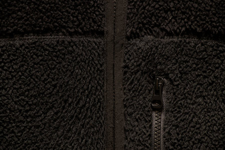 Black warm sweater with a zipper and a pocket with a zipper as a background, synthetic material, black clothesの写真素材