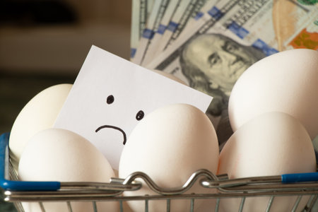 Chicken eggs in a supermarket basket on the table and a sad drawing on paper, egg shortage in Americaの写真素材