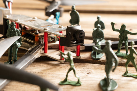 A downed FPV drone lies on a wooden board surrounded by children's plastic soldiersの写真素材