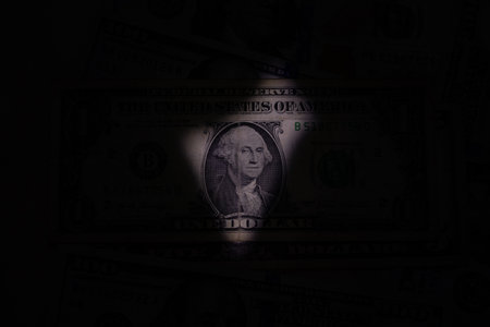 One dollar in the dark and a beam of light directed at the bill, American moneyの写真素材