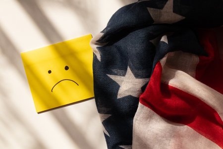 Drawn sad emotion on yellow paper on white background and shadowsの写真素材