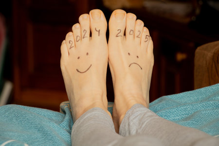 Drawing 2024 with a smile and 2025 with sadness, drawn on the legs of a girl lying on a bed at home, bad and good yearの写真素材