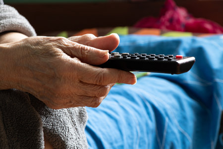 Elderly woman hand holding remote control at home,watching TV,viewerの写真素材