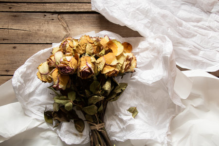 Large bouquet with roses and white wrapping on the table in disassembled form, bouquet of dried...