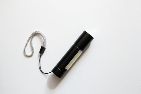 Small pocket portable black flashlight with led bulbs on white backgroundの写真素材
