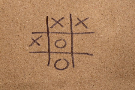 Children's game tic-tac-toe drawn on brown paper with black markerの写真素材
