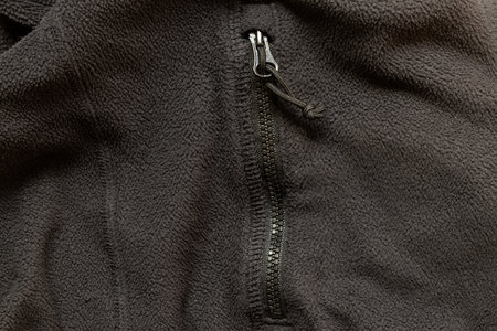 Texture of black fleece jacket with zipper on pocket close-up, fabric and fittings, zipper on jacket