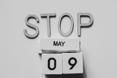 White wooden cubes with the date May 9 and the word stop on a white background.