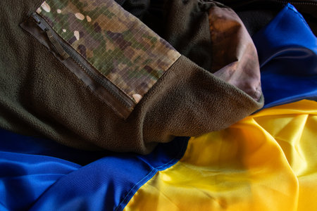 Warm camouflage uniform of Ukrainian soldier lies on Ukrainian flag, soldier uniform in Ukraineの写真素材